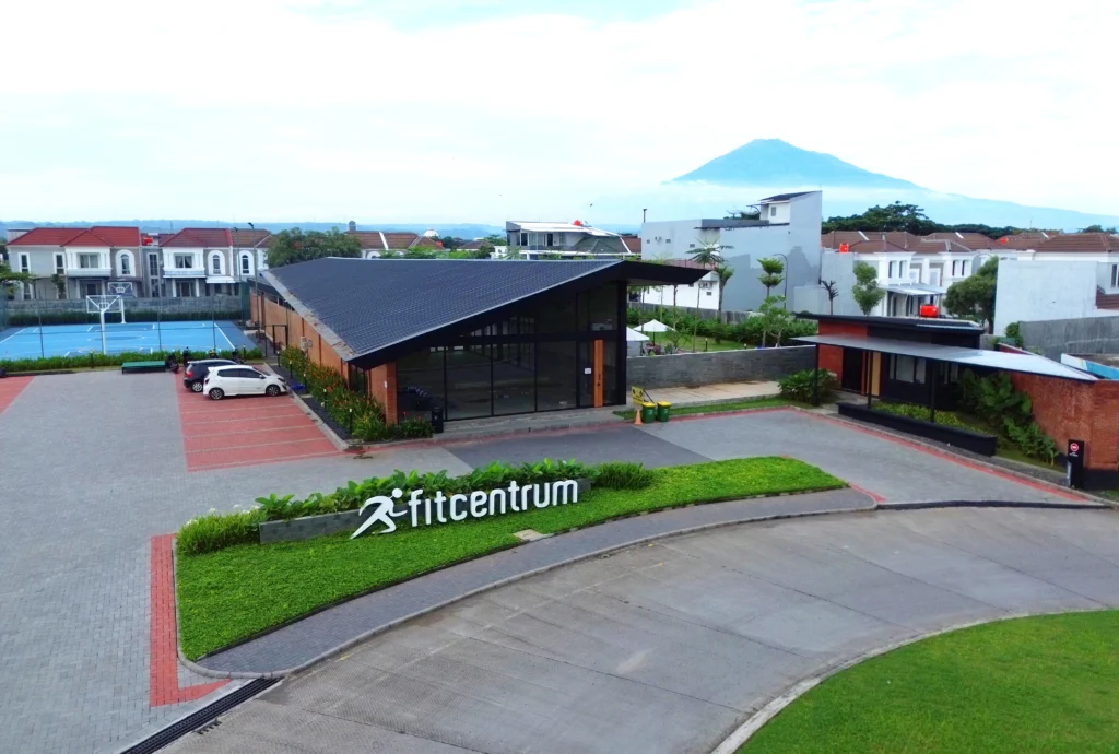 Gedung Family Sports Club (Fitcentrum) CitraLand Cirebon dengan desain modern industrial, lapangan olahraga, dan latar belakang Gunung Ciremai.